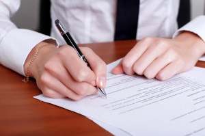 Person's hand signing an important document