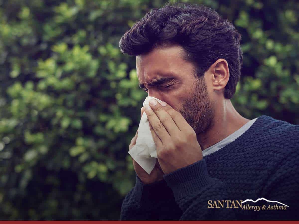 Man sneezing outdoors due to Allergies during monsoon season